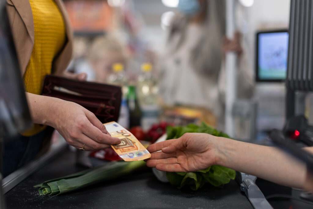 Close-up of woman giving money at the cash desk in supermarket